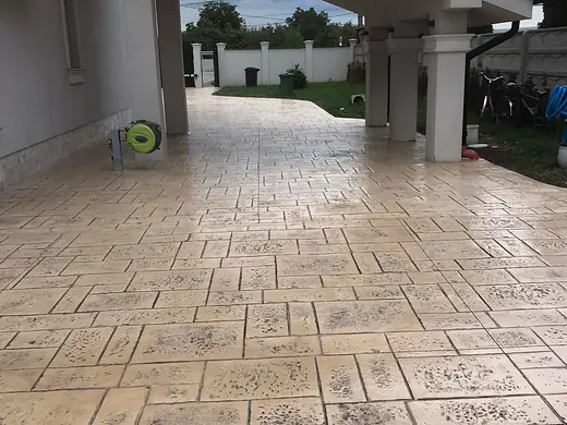 Zufahrt aus Prägebeton, die unter dem Vordach zur Garage führt