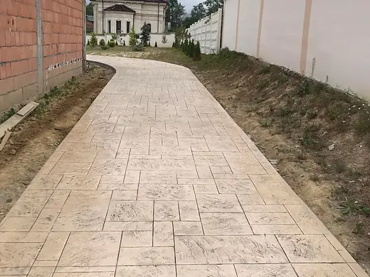Seitenweg aus Prägebeton entlang eines Nebengebäudes