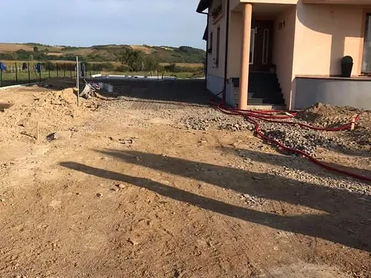 Ausgehobenes Erdplanum vor einem Haus am Hang