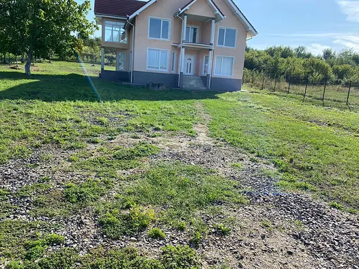 Unbefestigte Fläche aus Gras und Kies vor einem Neubau