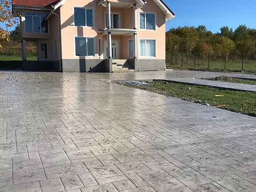 Fertige Zufahrt aus hellgrauem Prägebeton vor dem Neubau