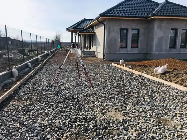 Verdichteter Kiesunterbau mit Nivelliergerät vor dem Betonieren