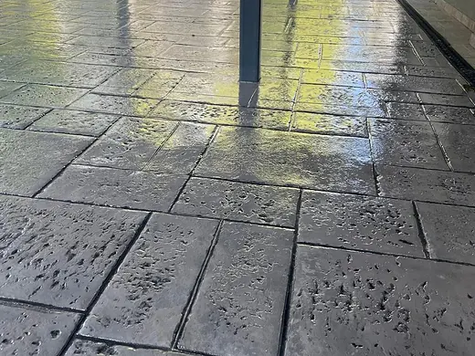 Grossformatige Plattenstruktur aus Prägebeton unter einem Carport, nass