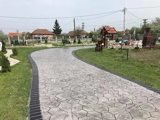 Geschwungener Gartenweg aus grauem Prägebeton in Bruchsteinoptik