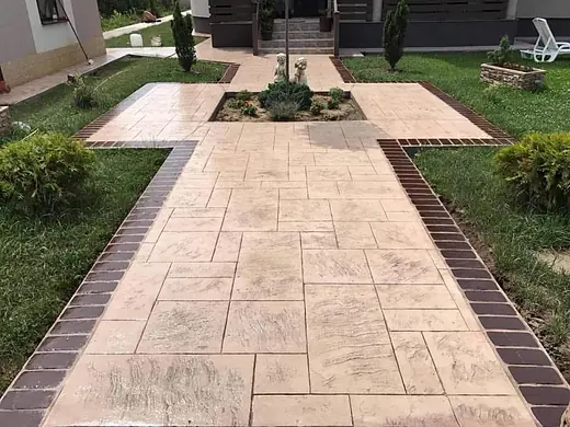 Symmetrisch angelegte Gartenwege aus hellem Prägebeton um einen Brunnen