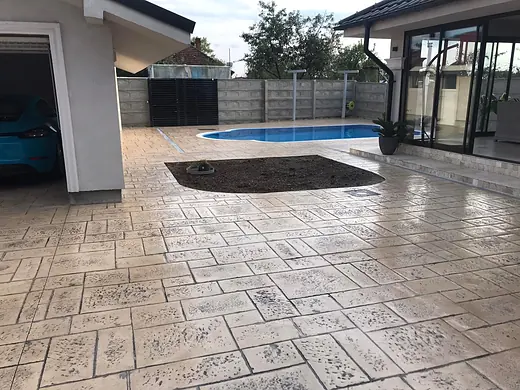 Poolterrasse aus Prägebeton vor einem modernen Haus mit grosser Glasfront