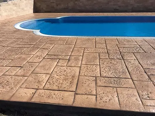 Freiform-Pool mit sandbeiger Umrandung aus Prägebeton