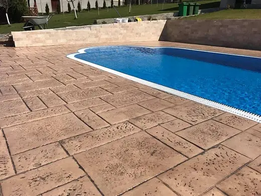 Schwimmbecken in Hanglage mit umlaufender Fläche aus Prägebeton