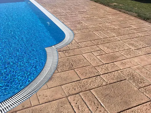 Schwimmbecken mit terracottafarbener Umrandung aus Prägebeton