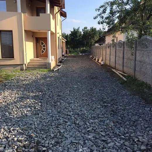 Grober Kiesweg zwischen Hauswand und Grundstücksmauer